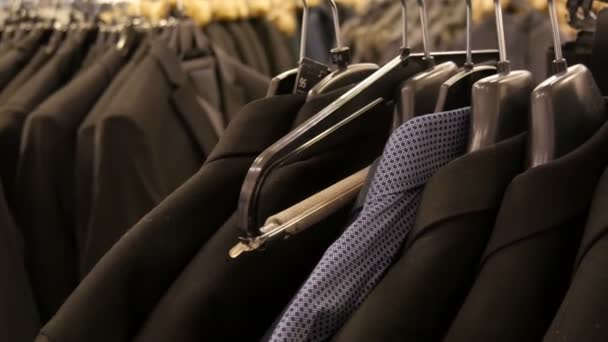 Un certo numero di diversi uomini alla moda giacche nere e camicie sulla gruccia nel negozio di abbigliamento maschile nel centro commerciale
. - Filmati, video