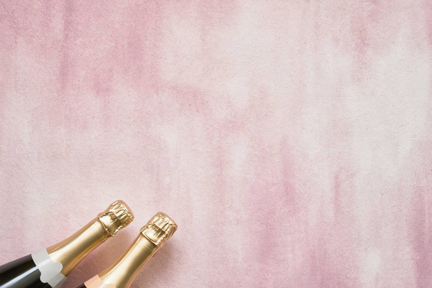 ピンクの背景に紙吹雪星と 2 つのシャンパンのボトル。トップ ビュー領域にコピーします。クリスマス、記念日、独身、新年お祝い概念のフラットを置く. - 写真・画像
