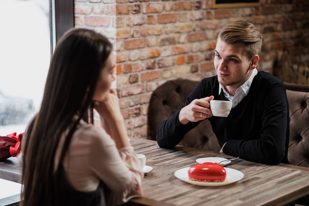 Mies katsoo tyttöä, kahvilapöydässä, juo teetä, rakastava pari
. - Valokuva, kuva