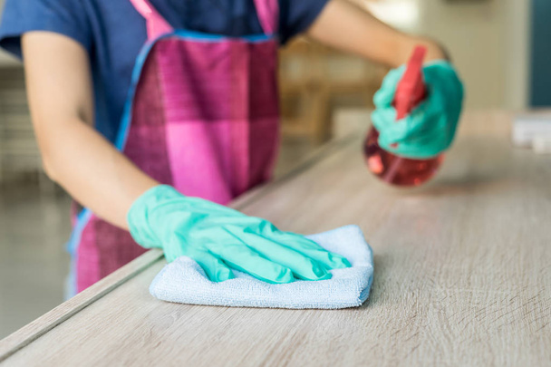 Mladá žena v ochranné rukavice pomocí prachovku a sprej na čištění nábytku - Fotografie, Obrázek