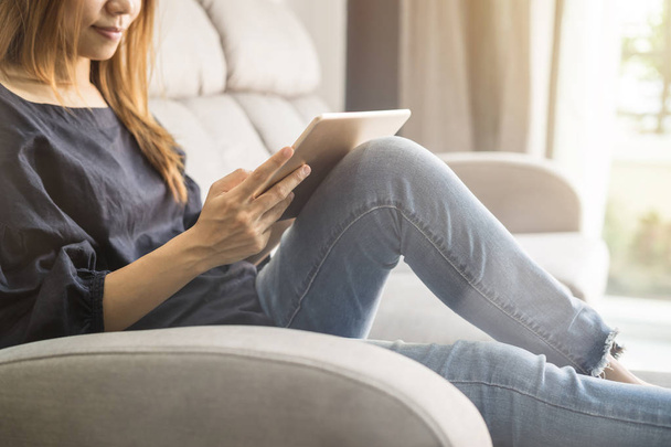 Young woman using tablet on sofa at home - Fotoğraf, Görsel
