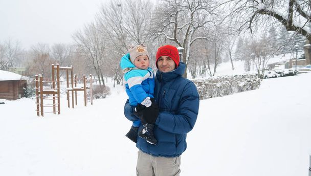 A portrait of father and little boy on a cold winter day. Family concept. Daddy holds his cute boy on his hands. - Fotó, kép