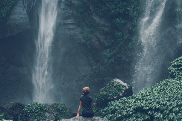 Young woman posing on a great Sekumpul waterfall in the deep rainforest of Bali island, Indonesia. - Foto, afbeelding