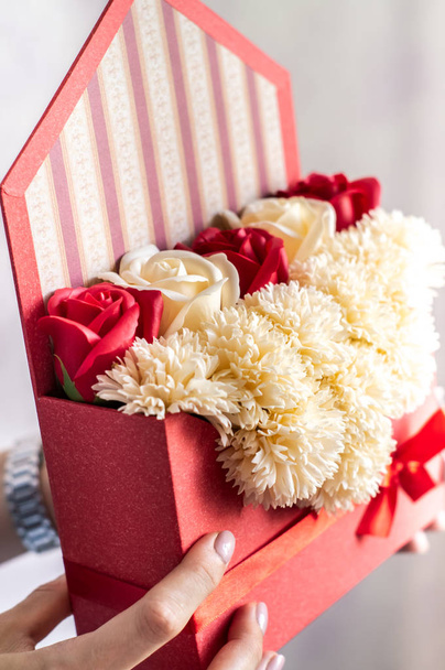 Flowers as a gift: Red striped vintage envelope with flower buds. - Foto, Imagem