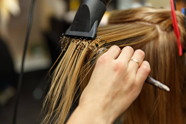 プロの美容師がサロンで彼女のクライアントの髪を染めます。ヘアドライヤーで乾燥した髪を Haircutter。選択と集中. - 写真・画像