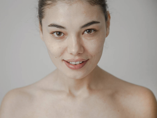 Gezonde huid vrouw mooi gezicht close-up over grijze achtergrond - Foto, afbeelding