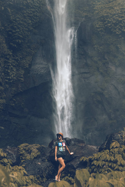 Mujer joven posando en una gran cascada de Sekumpul en la selva profunda de la isla de Bali, Indonesia
. - Foto, imagen