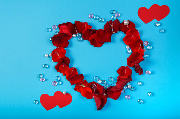A heart lined with rose petals on a blue background in the design of white and pink beads. - Foto, Imagem