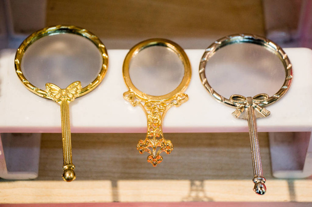 Kis dekoratív arany színű kézi tükör a polcon - Fotó, kép