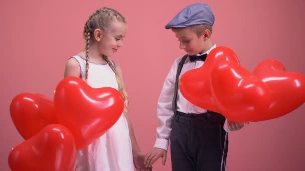 Roztomilý malý pár s balónky, drželi se za ruce a s úsměvem, děti na den lásky - Záběry, video