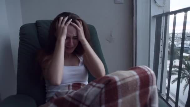 Fiatal depressziós nő húzza a haját a kezével, és sírva ült az ablak mellett. Esik az eső kívül. Magányos nő a kétségbeesés és öngyilkossági gondolatok. - Felvétel, videó