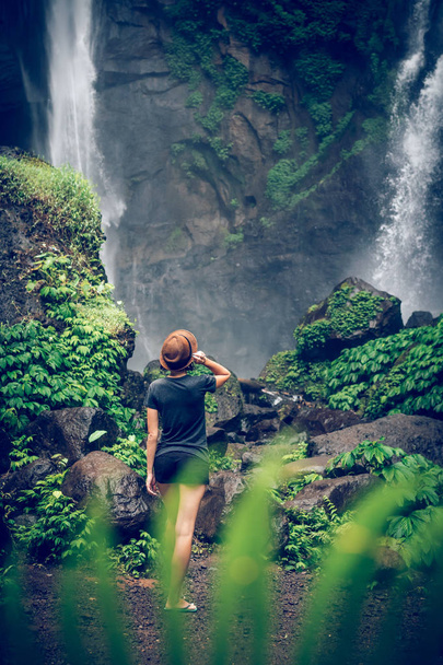 junge Frau posiert auf einem großen sekumpul-Wasserfall im tiefen Regenwald der Bali-Insel, Indonesien. - Foto, Bild