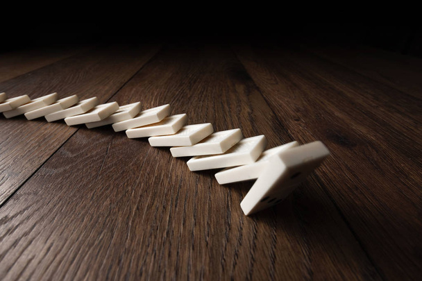 Creative background, white domino, on brown wooden background. Concept of domino effect, chain reaction, risk management, copy space. - Zdjęcie, obraz