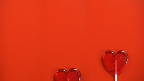 St Valentines Day text and heart-shaped lollipops appearing on red background - Séquence, vidéo