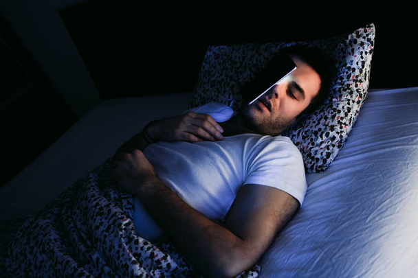 Mladý muž pomocí smartphone v posteli v noci - Fotografie, Obrázek