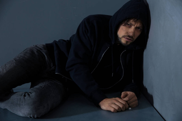Young addicted man sitting near brick wall after using drugs - Фото, зображення