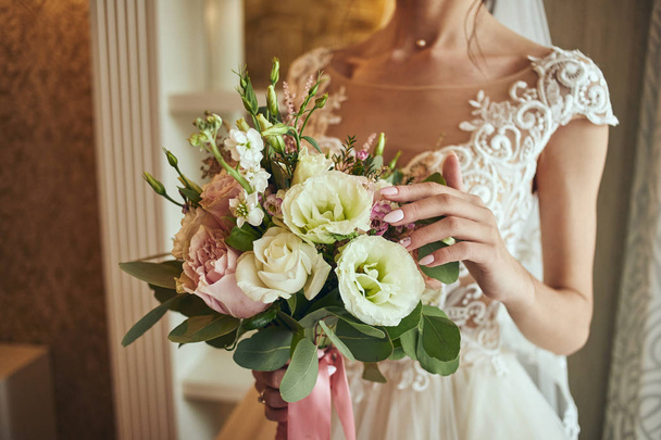 bouquet in hands of the bride, woman getting ready before wedding ceremony - Foto, afbeelding