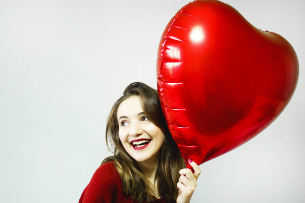 Piękna młoda kobieta z balonem kształt serca na szarym tle. Walentynki. - Zdjęcie, obraz