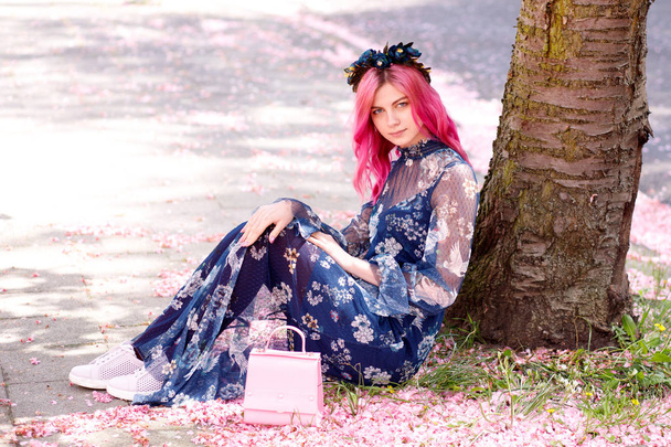 young beautiful girl with pink hair standing near a tree with flowers, pink flowers, spring, sun, happiness - 写真・画像