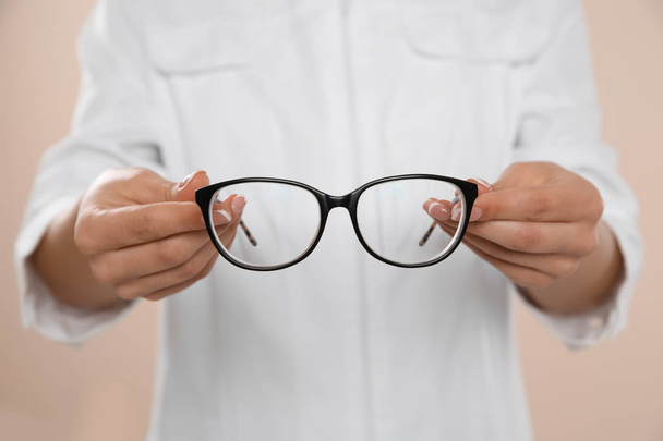Female ophthalmologist with eyeglasses on light background, closeup - Photo, image