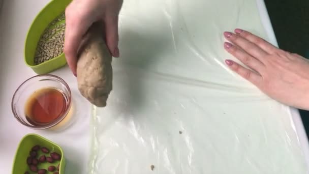 A woman rolls a sausage from a mixture with crushed peanuts, sunflower seeds and honey. Homemade halva cooking. - Séquence, vidéo