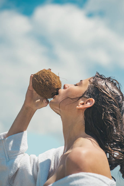 vegetarian and vegan. Woman is moisturizing her skin with a coconut cream. coco milk. drinking beach cocktail. woman drinking coconut juice. summer vacation. coconut oil production - Foto, Imagem