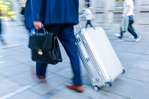 motion blur picture of a businessman walking with a trolley case in the city - Foto, Bild