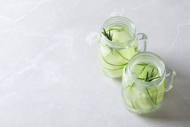 Mason jars of fresh cucumber water on grey background. Space for text - Φωτογραφία, εικόνα
