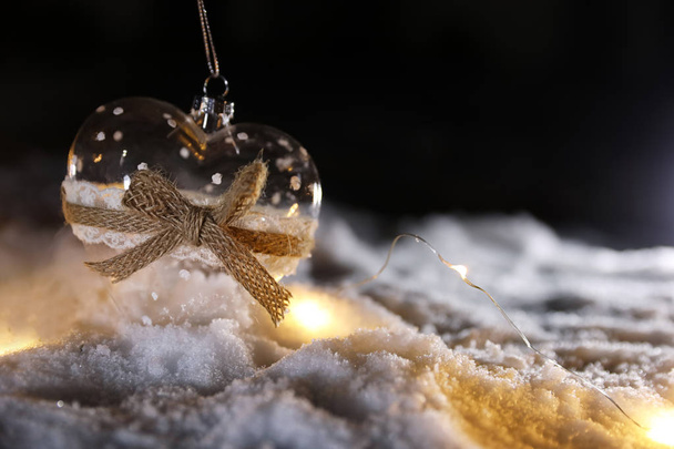 Glass heart and fairy lights on white snow outdoors. Space for text - Fotografie, Obrázek