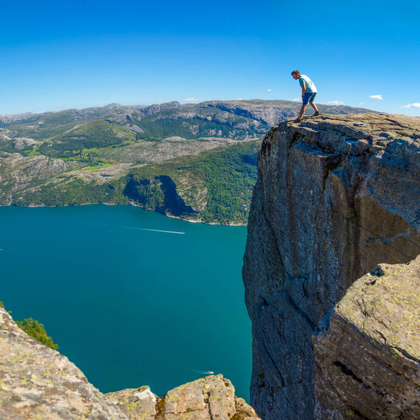 Πεζοπόρος στέκεται στο Preikestolen και ψάχνει για το fjerd, Preikestolen - διάσημο απότομο βράχο στο νορβηγικό βουνά - Φωτογραφία, εικόνα