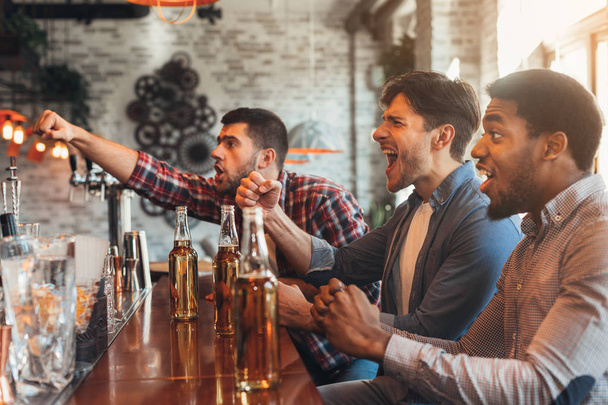 Diverse friends watching football game in bar - Photo, Image