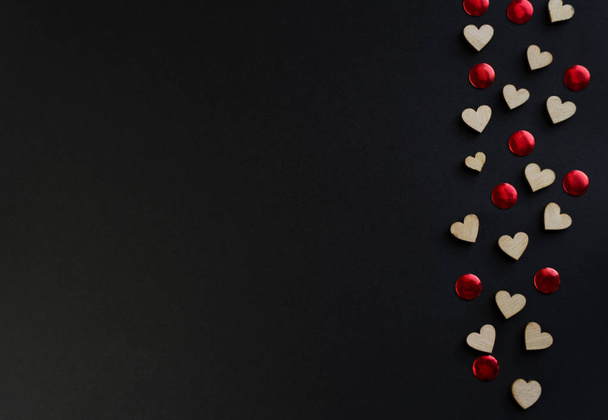Valentine's Day background with hearts, borders of large and small felt hearts on a black table, flat lay. The concept of Valentines Day. - Fotó, kép