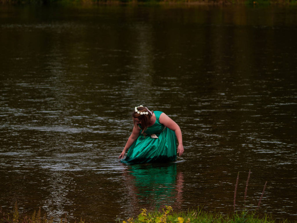 Portrait d'une jeune femme joyeuse dans une rivière vêtue d'une robe de fête verte
 - Photo, image