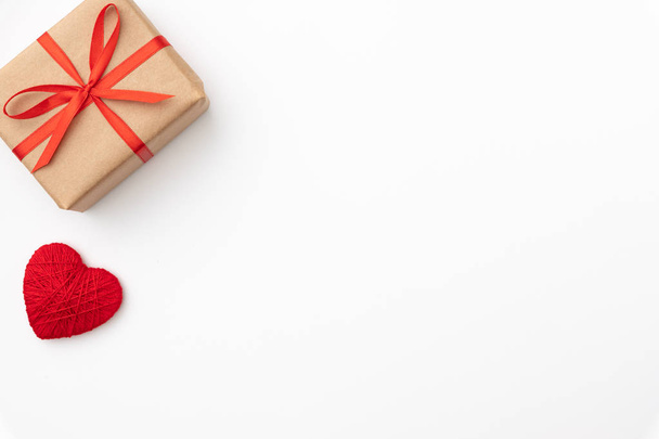 Décoration Saint-Valentin avec boîte cadeau en papier artisanal avec ruban rouge et petits cœurs rouges isolés sur fond blanc. Vue de dessus. Love day concept flat lay
 - Photo, image