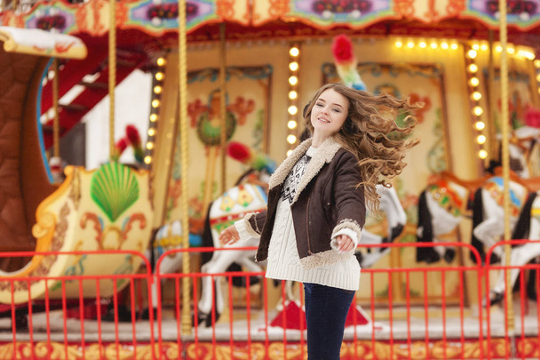 Beautiful happy woman with long vawy hair smiling over winter carousel . - Photo, Image