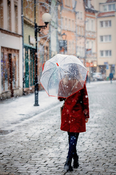 Красивая взрослая девушка в красном пальто и шарфе с зонтиком белый снегопад остаться на улице города
 - Фото, изображение
