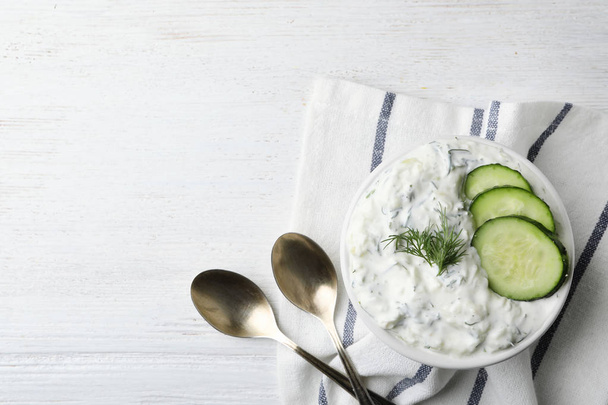 Cucumber sauce, spoons and space for text on wooden background, flat lay. Traditional Tzatziki - Fotografie, Obrázek