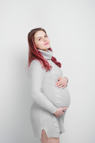 A pregnant woman with colored crimson hair in a knitted gray pullover. - Photo, Image