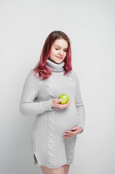 A pregnant woman is holding green and red apples. - Valokuva, kuva