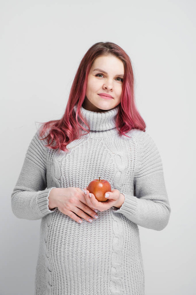 A pregnant woman is holding green and red apples. - Foto, imagen