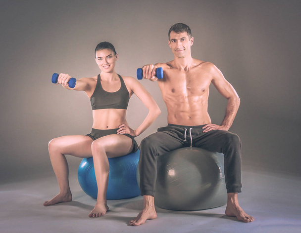Two smiling people with fitness ball in the gym. Personal fitness instructor. Personal training. Gym workout. - Photo, Image