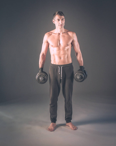 Handsome muscular man working out with dumbbells. Personal fitness instructor. Personal training. - Fotoğraf, Görsel