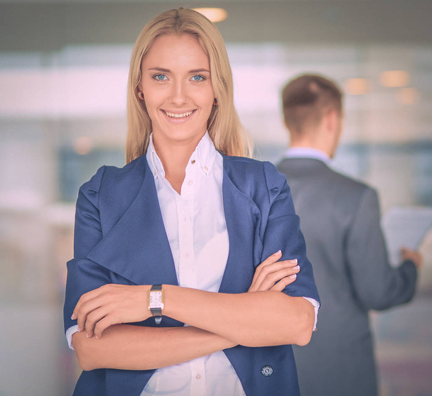 Portrait of young businesswoman in office with colleagues in the background - Фото, изображение