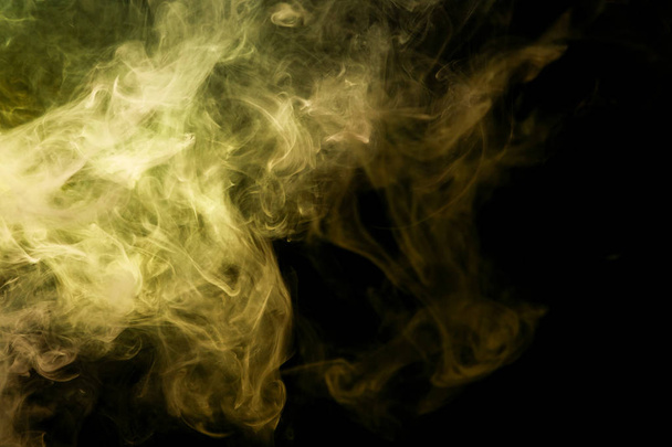 Thick yellow and orange smoke on a black isolated background. Background from the smoke of vap - Photo, Image