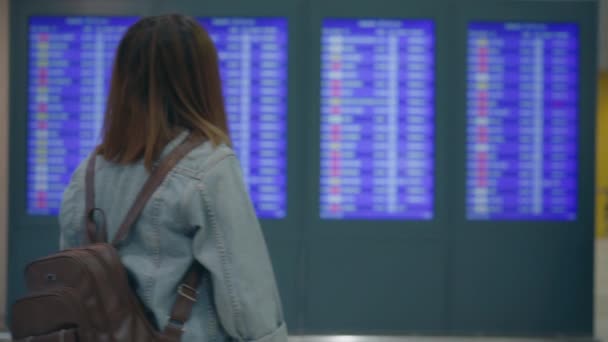 Slow motion - Happy Aziatische vrouw kijken informatiebord controleren haar vlucht met bagage in terminal hal bij de gate van vertrek in de internationale luchthaven. Levensstijl vrouwen gelukkig in luchthaven concept. - Video