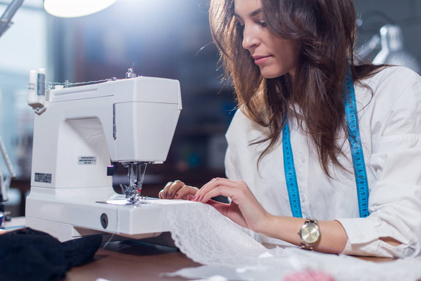 Imagen recortada de costura de sastre femenino encaje fino con máquina de coser sentado en estudio de costura
 - Foto, imagen