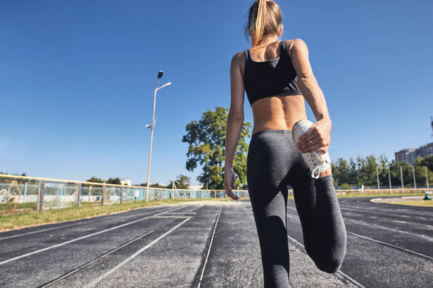 Young runner fit woman streching before exercises outdoors. Athletic female strech after workout outside. Sport and people concept. - Fotoğraf, Görsel