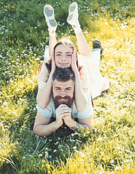 Man and woman laying on grass spring day. Spring leisure concept. Couple on happy smiling faces laying at meadow, nature on background. Couple in love spend time outdoors and hugs. - Photo, Image
