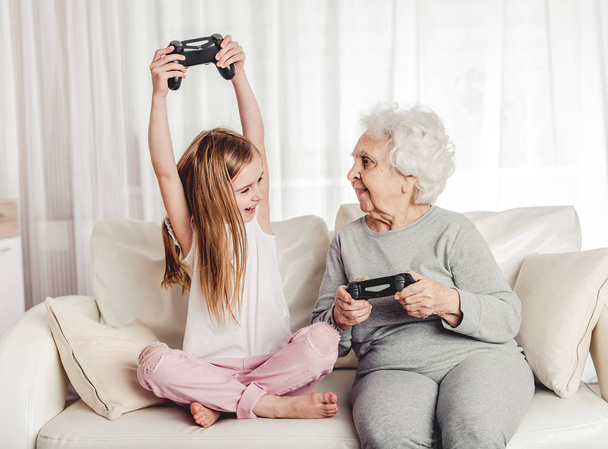 Grandmother with granddaughter playing games - 写真・画像