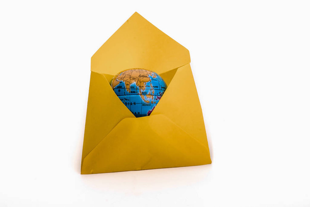 Klein aardemodel in een gele envelop op een witte achtergrond - Foto, afbeelding